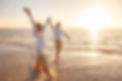 Happy senior couple joyfully playing in ocean waves at sunset