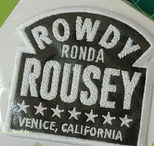 黑色斜紋布底,白線繡字與邊框製成造型臂章,上面繡的選手名稱用鏈目繡呈現。