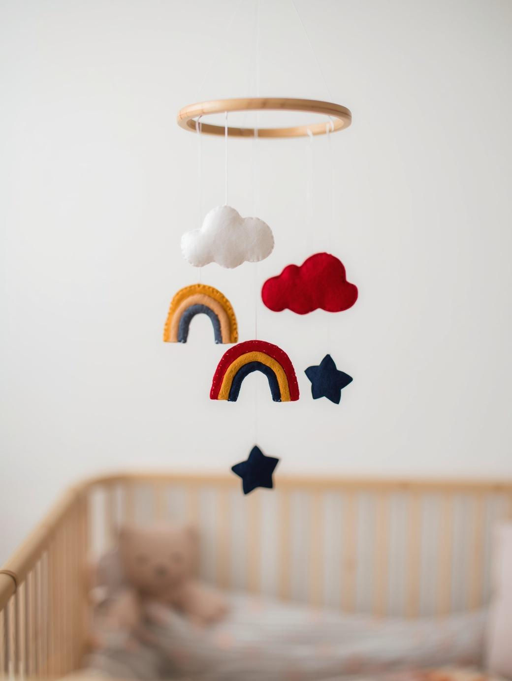 Completed DIY baby mobile featuring felt blue rainbows, fluffy clouds, and stars hanging from a wooden ring.