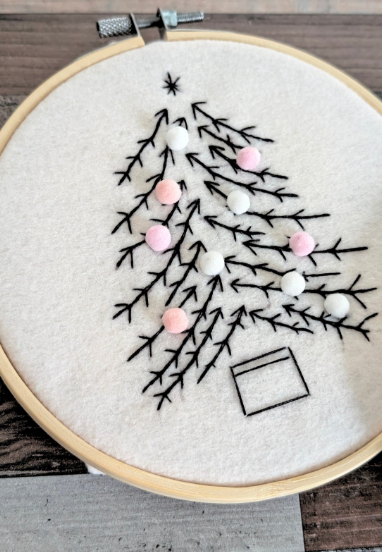 Thumbnail: Flat lay of Christmas embroidery craft kit showing felt pieces, threads, hoops, needles, and printed pattern sheets.