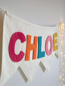 Handmade felt letter bunting spelling a name or phrase, used as personalised wall decoration in a young girl's room.
