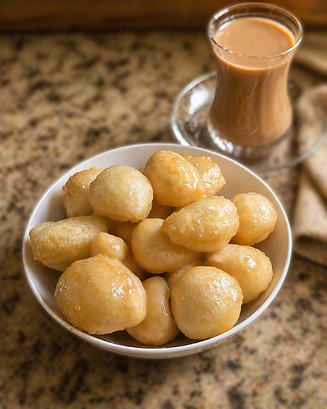 Donut Balls glazed with a light syrup with a cup of tea.