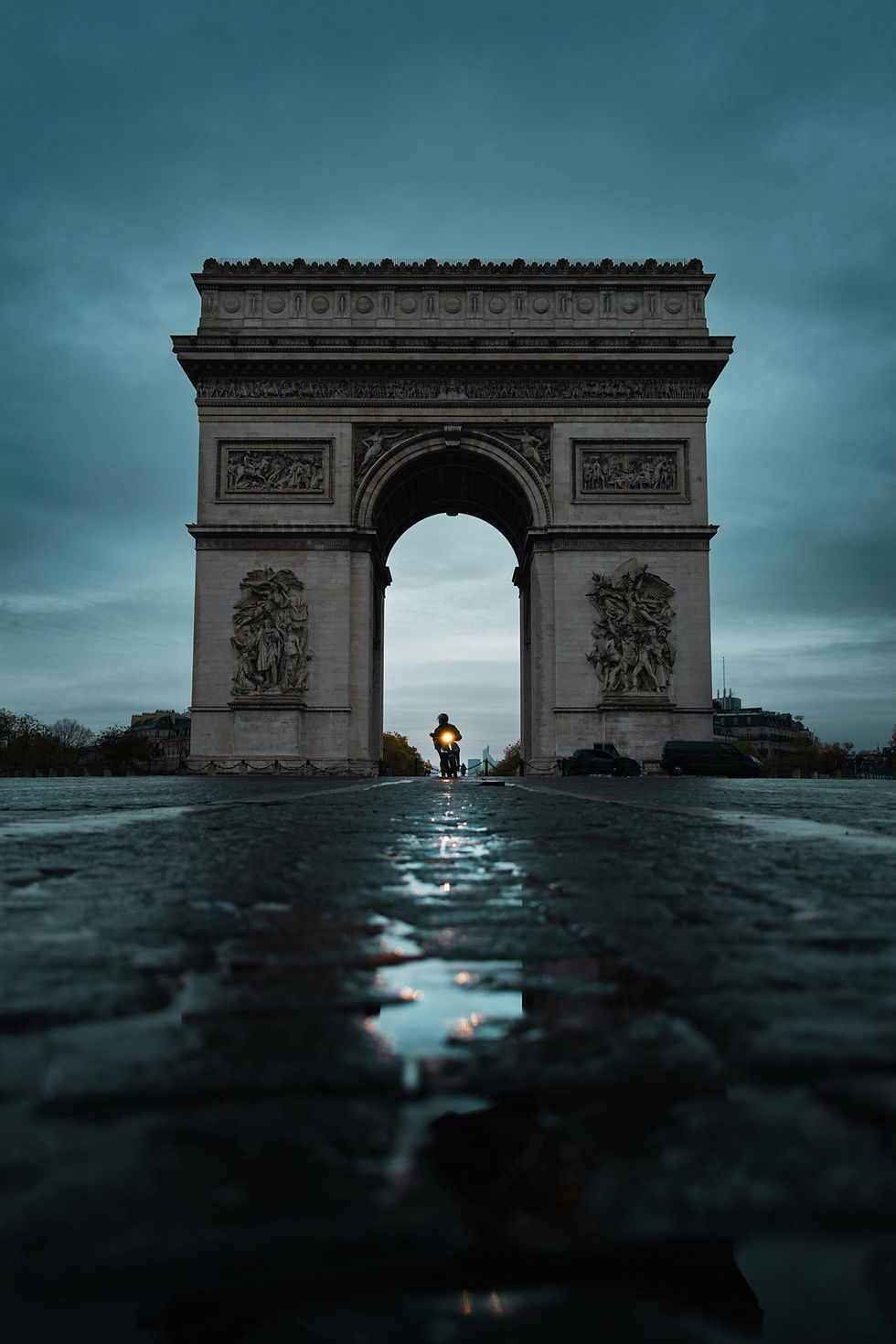 Runner passing under the Arc de Triomphe in Paris on a wet morning