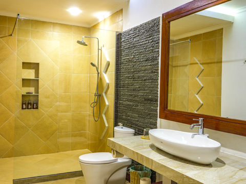 Modern bathroom with shower, toilet, sink, mirror and stone wall decor.