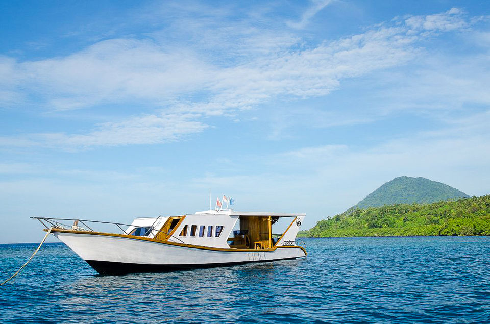 White boat floats on blue water with a mountain in the background.
