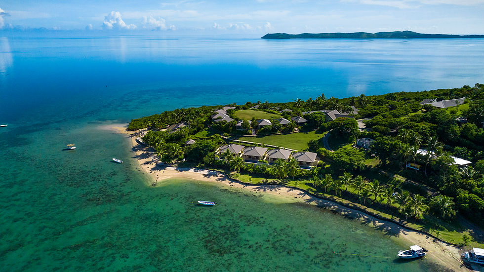 Thumbnail: Aerial view of a tropical island, lush green vegetation, and boats on water.