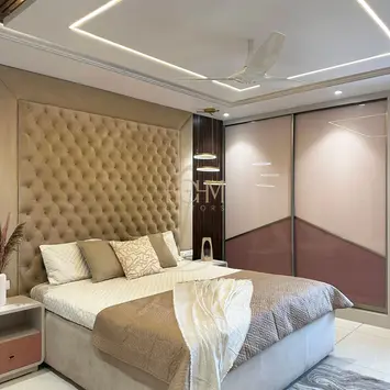 Modern master bedroom designed by hohm editors, interior designers in Hyderabad, featuring a king-size bed with neutral linens, feature accent wall with three-dimensional geometric panels, mirrored sliding wardrobes, statement recessed ceiling lighting, and plush bedside rug—creating a refined sanctuary with contemporary style and layered textures.