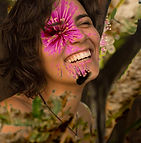 foto de Catarina, mostrada de peito para cima. Ela tem pele clara, cabelos curtos e castanhos. Sorri, com os olhos semicerrados. Sobreposta a foto, na altura do olho de Catarina, está o desenho de uma flor cor de rosa.