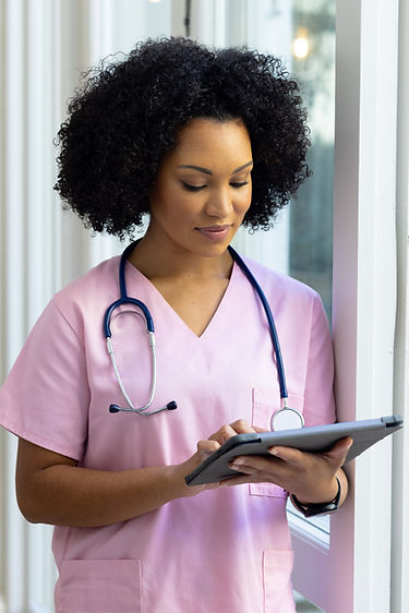biracial-female-nurse-wearing-pink-scrubs-reviewing-notes-tablet-home.jpg