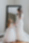 A bride and flower girl stand in front of a mirror in the Bridal House at our wedding venue near Nashville. 