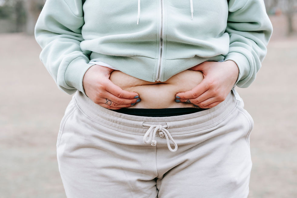 A woman in casual attire embracing her belly.