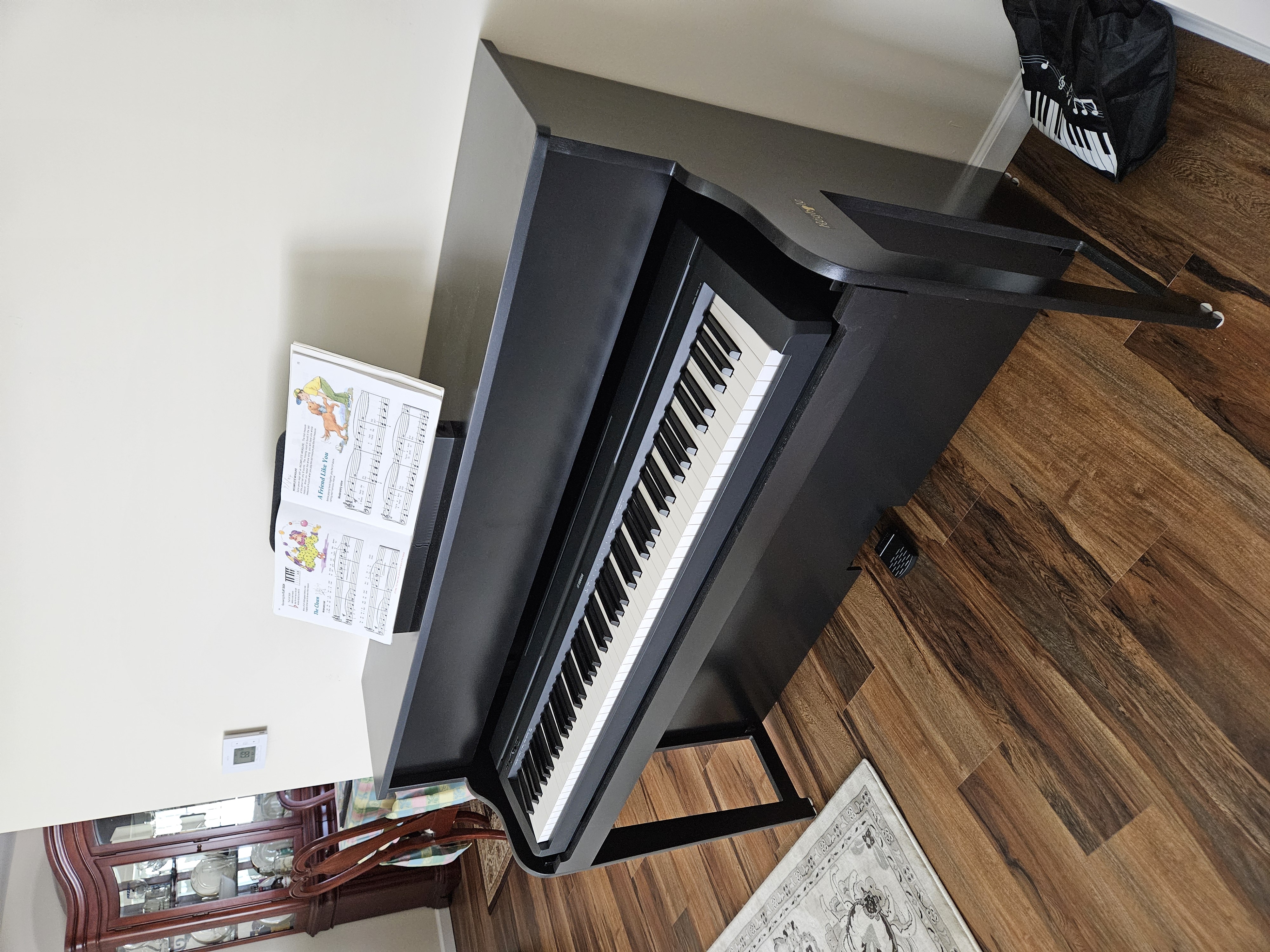 A black Keyhole upright with sheet music on its stand