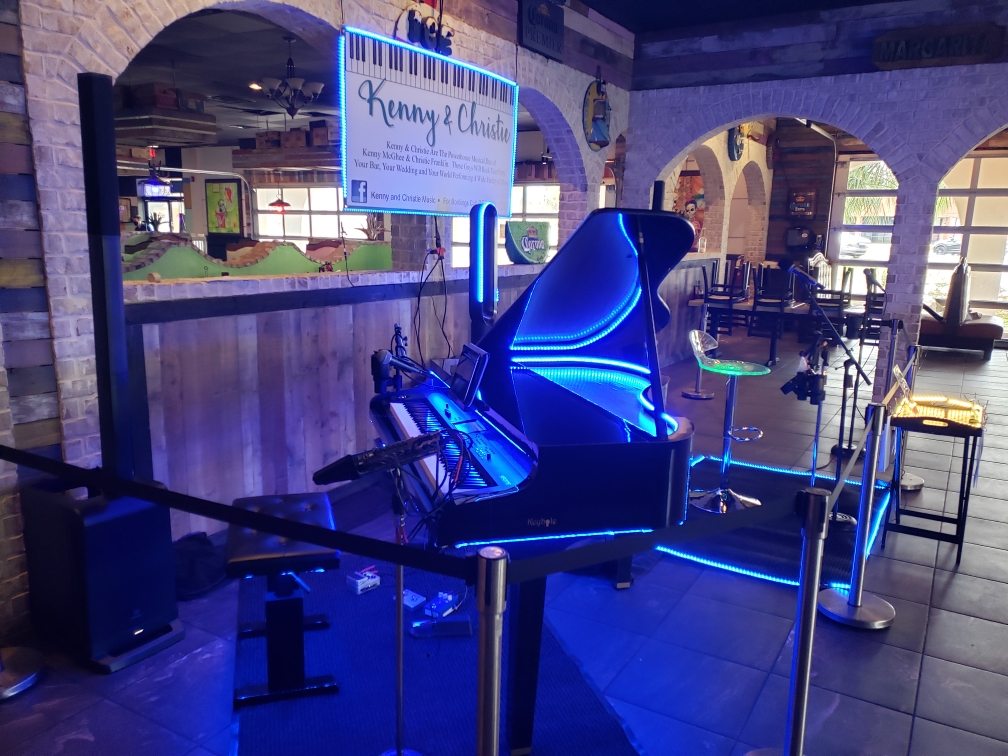 A Keyhole grand piano shell lit in blue at a bar