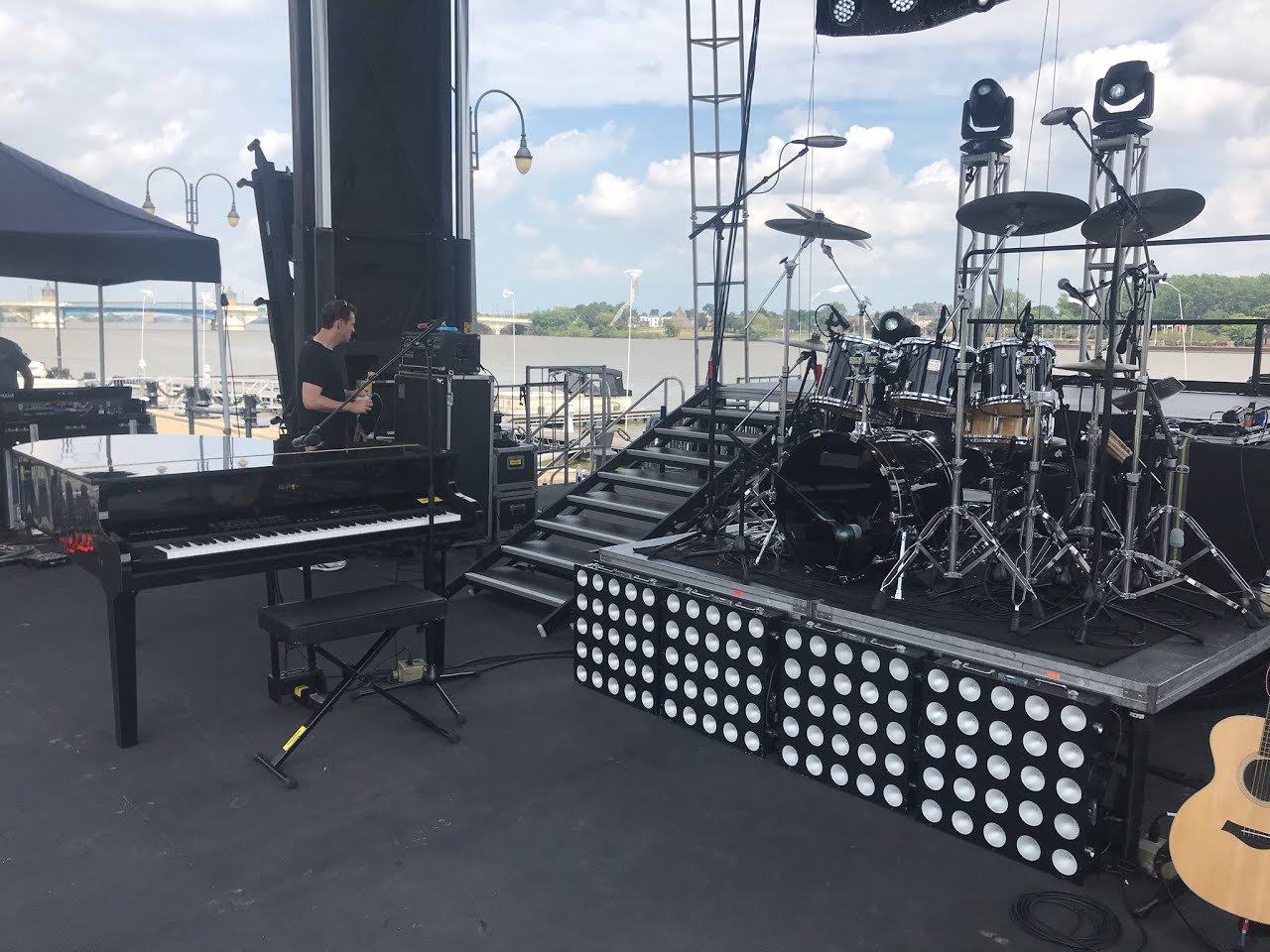 A Keyhole grand on an outdoor stage beside a drum riser
