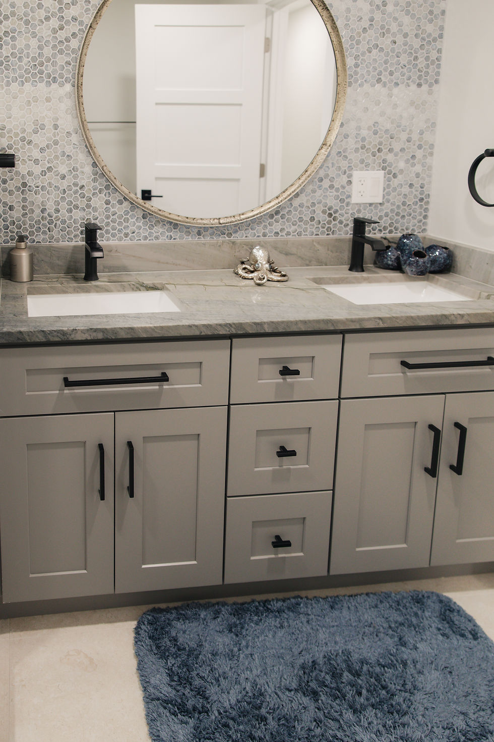 Modern double vanity bathroom design with round mirror and marble backsplash