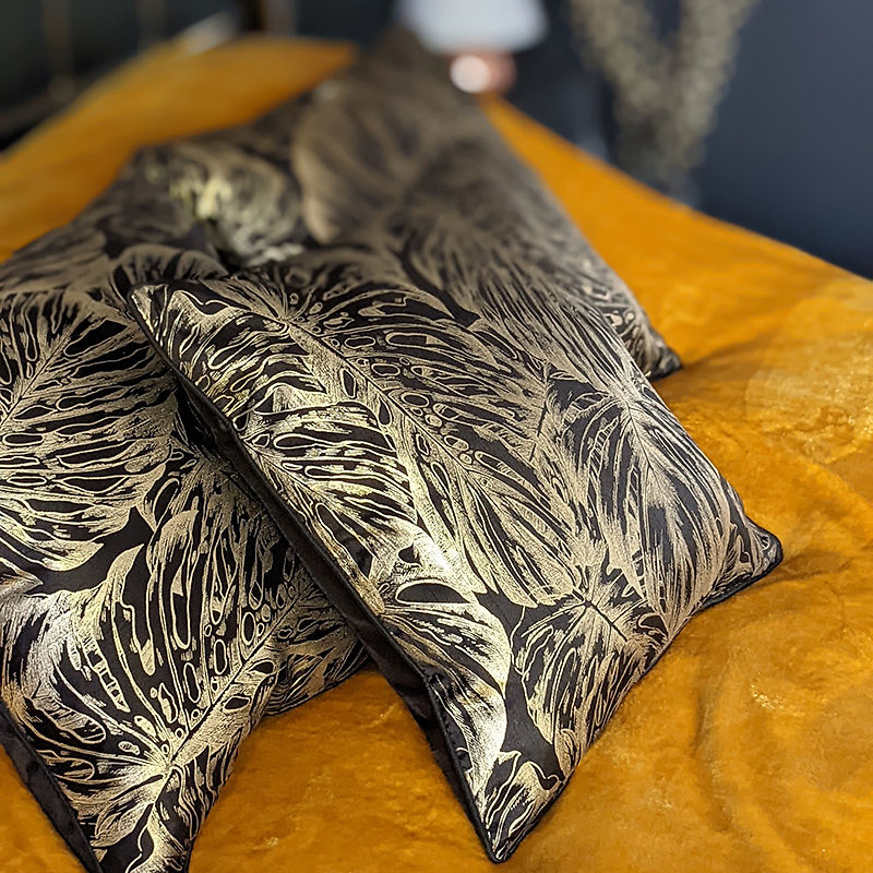 OAT Interiors: decorative gold leaf pillows on a yellow bed