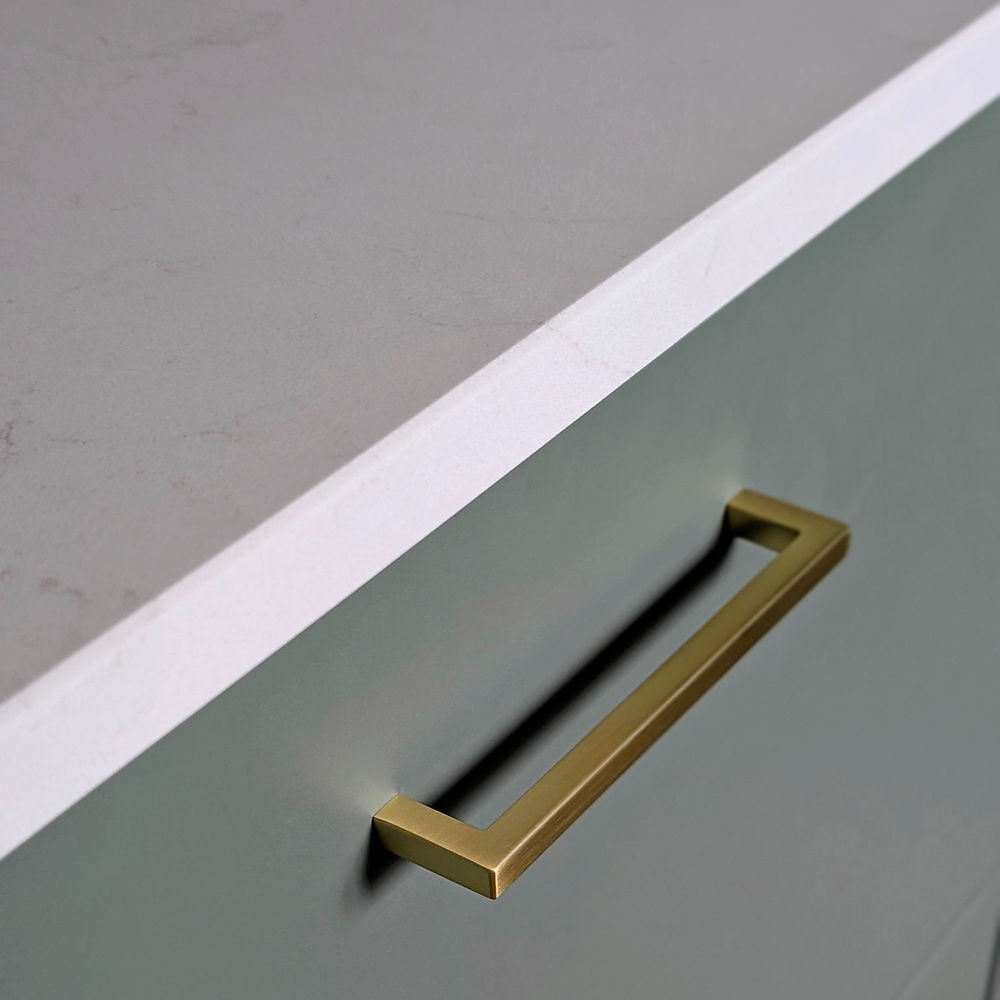 Modern brass handle on a light green cabinet
