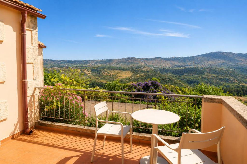 Balkon des Terrassenzimmers mit Tisch und Stühlen und Blick auf die Hügel.