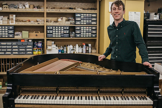 Brad Fant smiling next to grand piano