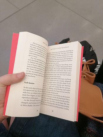 A hand holds a book open and shows off a subtitle stating "fuck facism" on page 84 of A Short History of Queer Women by Kirsty Loehr