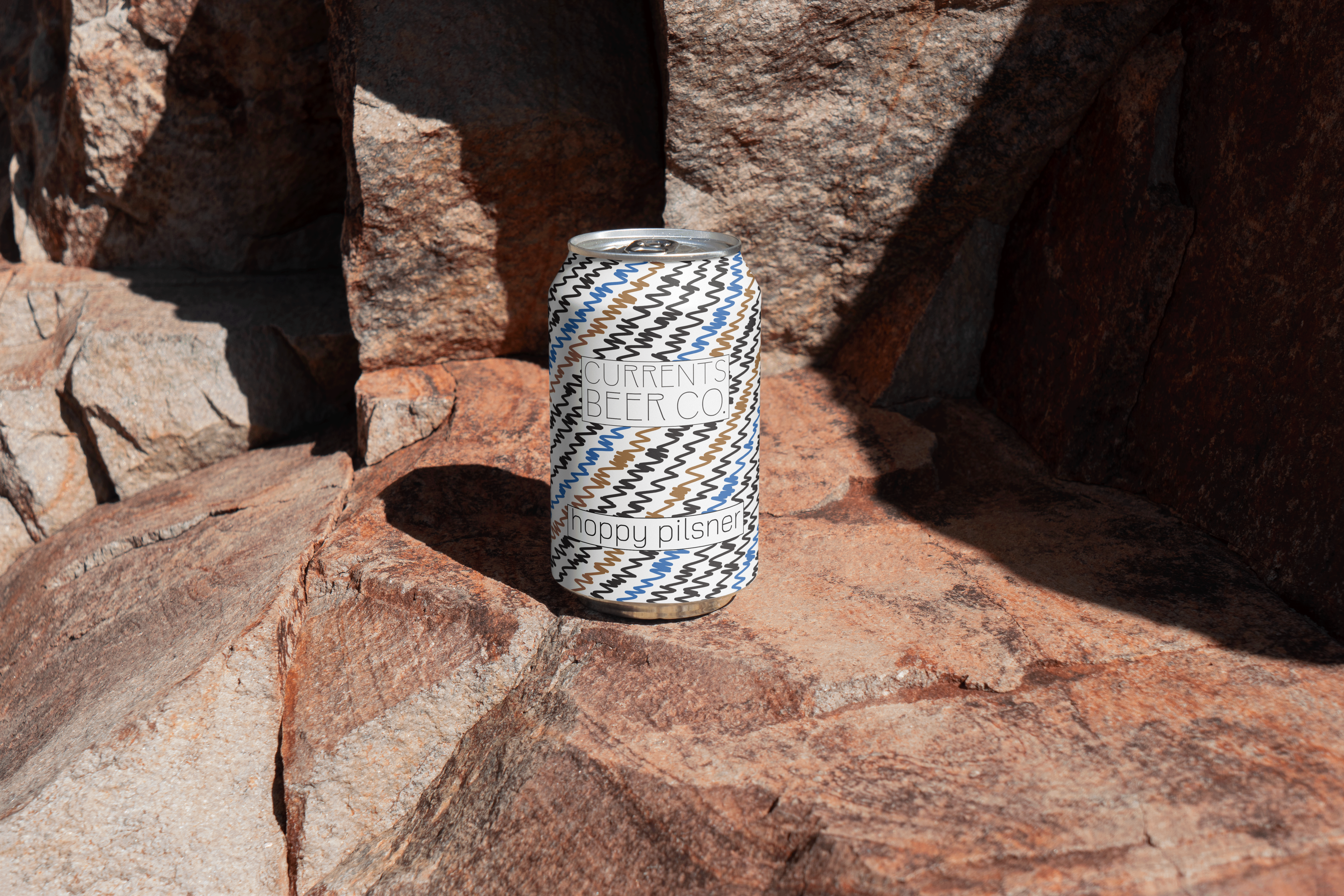 Beverage can packaging design photographed outdoors featuring patterned label design and natural tex