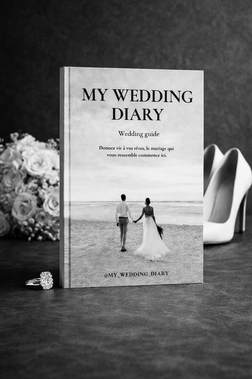 Livre blanc My Wedding Diary sur table, avec bouquet, alliance et escarpins, ambiance élégante.