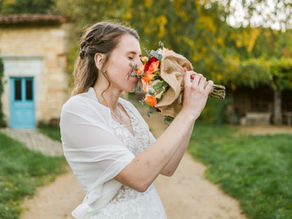 Mariée qui sent son bouquet de fleurs le jour de son mariage aux Vieux métiers à Azannes et Soumazannes avec Nina Photographie, photographe de mariage lumineux et élégant