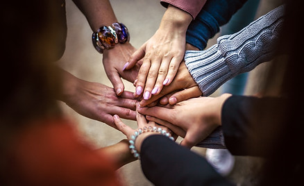 Manos de distintas personas unidas representando trabajo en equipo.