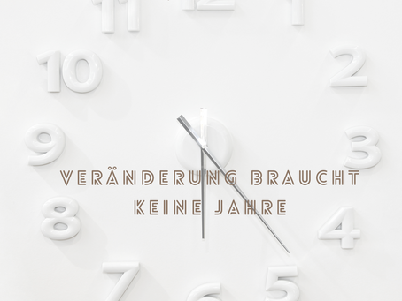 Helle Uhr mit sichtbaren Ziffern und der Aufschrift „Veränderung braucht keine Jahre“