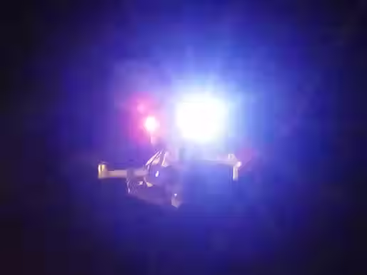 A DJI mavic 3 drone can be seen with mounted searchlights from drone sky hook with a dark background