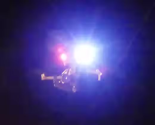 A DJI mavic 3 drone can be seen with mounted searchlights from drone sky hook with a dark background
