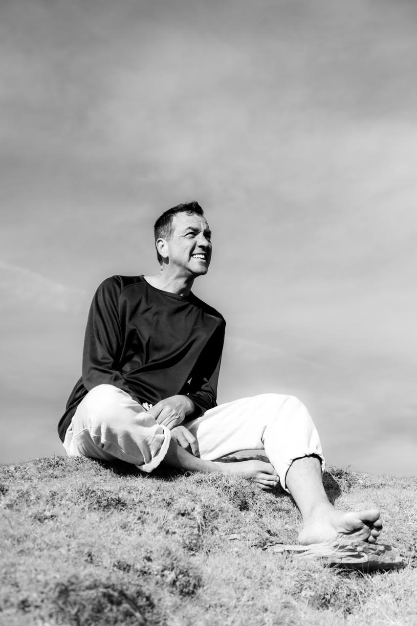 Bruce seated outdoors, smiling, in a black-and-white portrait