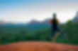 A woman standing in a yoga pose atop red mountainous rock