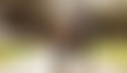 Child learning to ride a bike with male adult's help