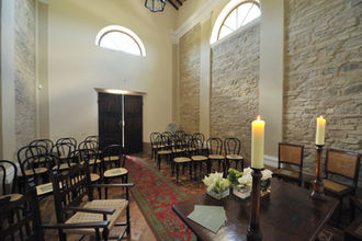 Chapel interior prepared for a wedding, with chairs and simple floral decorations.