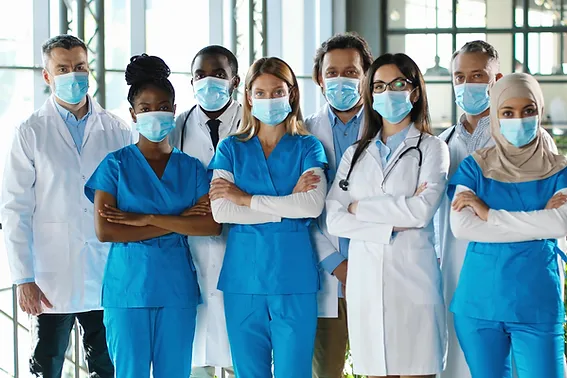 Mixed-races busy team of male and female doctors posing to camera and crossing hands in ho