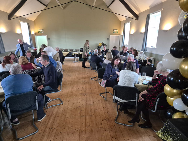 Group of people seated around tables at a community event Thorpe Satchville Vi