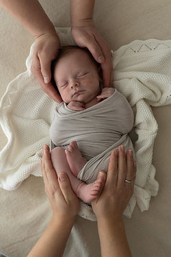 Unbearbeitetes Foto eines Neugeborenen welches von Mamas und Papas Händen gehalten wird