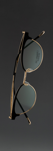 Minimalist product photograph of women’s cat-eye sunglasses floating against a soft dark gradient background. The frames feature refined craftsmanship and subtle color variations in titanium and acetate materials, highlighting modern eyewear design and elegant contours