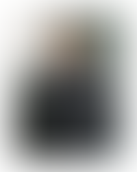 Model wearing KP-281U eyewear by KIO YAMATO, styled in a dark robe with subtle pink accents, photographed front-facing in soft architectural light.