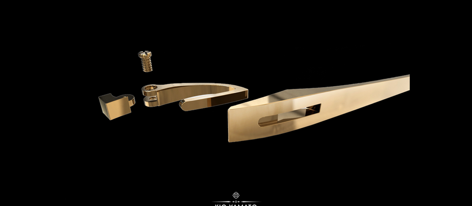 Exploded view of a gold-tone KIO YAMATO eyeglass hinge, showing a curved connector, hinge pin, and temple arm with a rectangular opening.