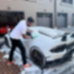 Owner Miles meticulously cleaning vehicle exterior with microfiber cloth, ensuring a thorough detailing job.