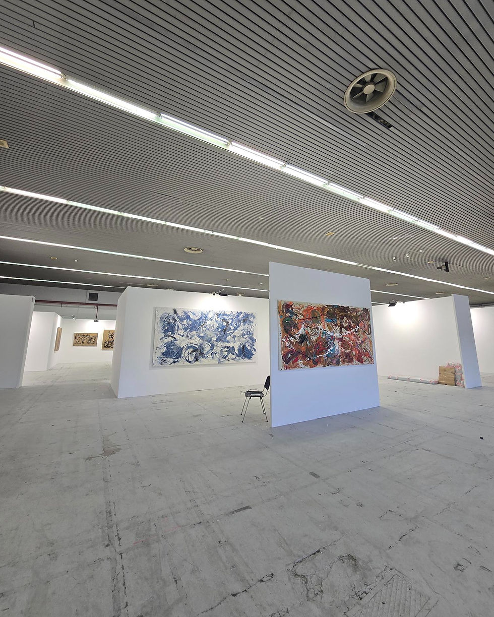 Abstract paintings installed within a spacious contemporary exhibition environment at the Thessaloniki Art Fair, emphasizing architectural placement, negative space, visual breathing room, and the relationship between art, environment, and long-term livability.