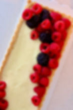 Torta de creme com framboesas e amoras sobre prato branco, vista de perto.
