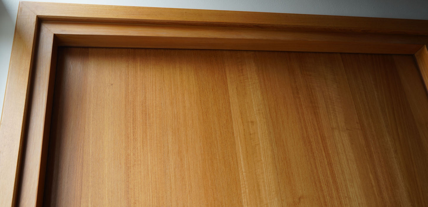 Extreme close-up shot of a perfectly constructed wood door frame joint, showing the precise joinery and craftsmanship quality standard of THAVII.