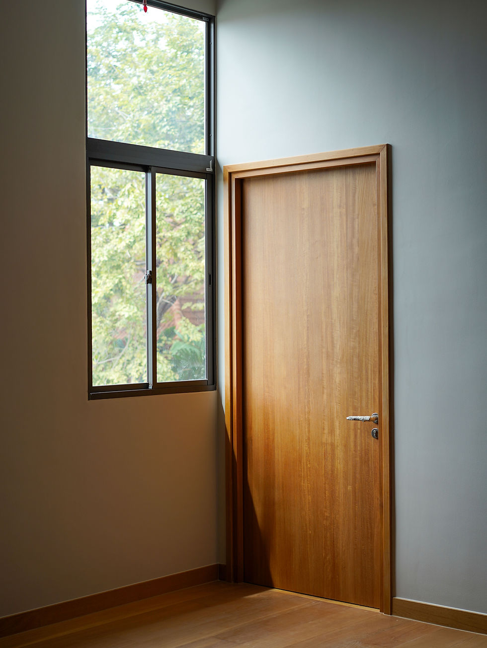 A modern luxury interior featuring a custom minimalist solid wood door by THAVII, representing the present-day, fourth-generation evolution of our Thai woodworking mastery.
