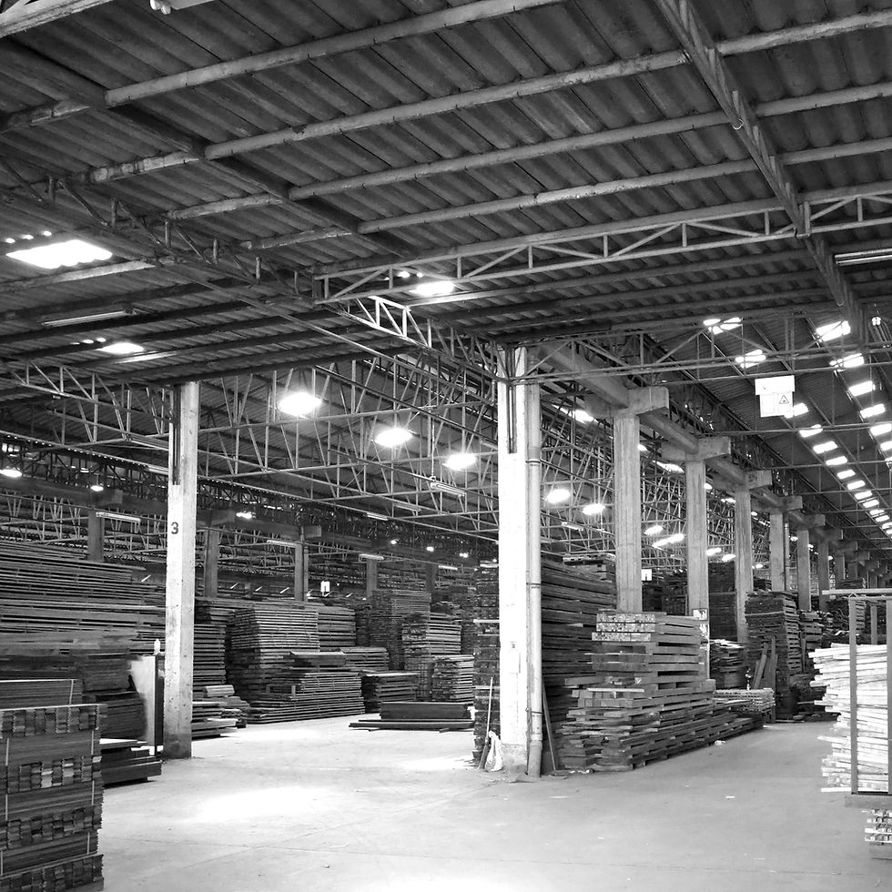 A photograph from 1987 showing the massive interior of the Taweerojn Wood manufacturing facility, filled with stacks of premium timber ready for architectural fabrication.