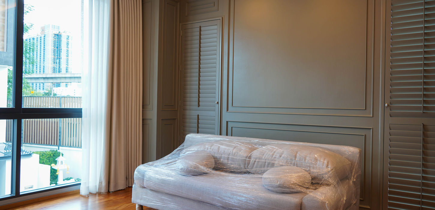 A luxury living room interior showing traditional dark wood wall paneling and integrated window shutters custom-built by THAVII in Bangkok, featuring a new sofa.