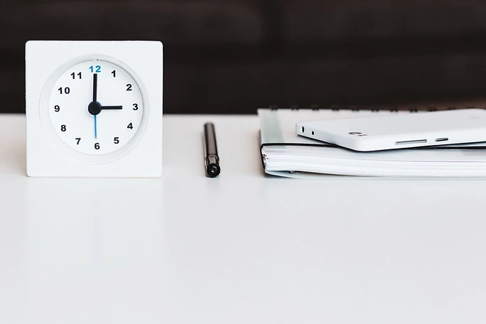 White Clock with Paraphernalia on Top of a White Tabletop