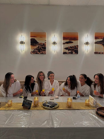 Group of women in robes sit around a table enjoying massage specials.